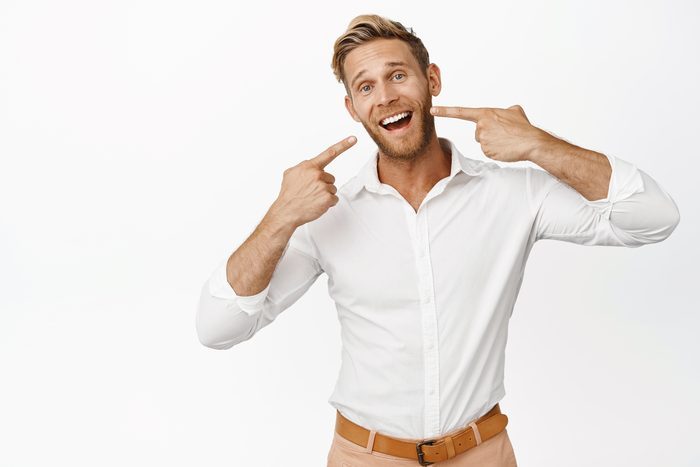 Businessman pointing with perfect smile, dental clinic advertisement